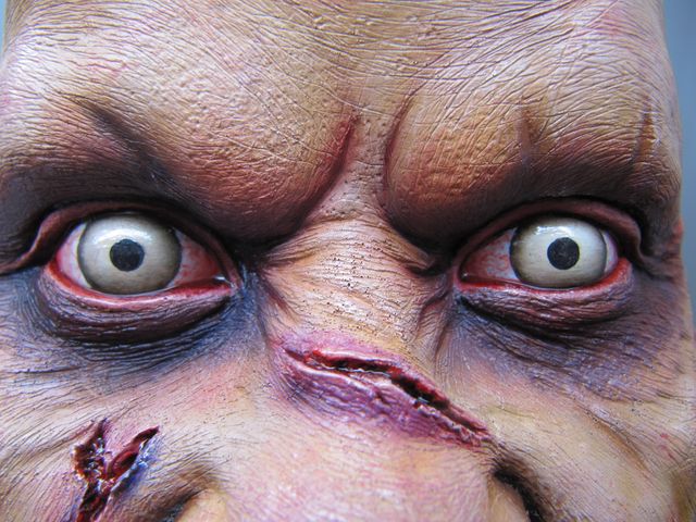 Gros plan du visage peint de Regan avec yeux clairs, sourcils froncés et plaies sanglantes