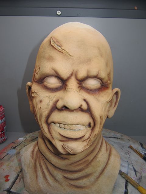 Buste sculpté du visage démoniaque de Regan, yeux blancs et peau cicatrisée, en cours de peinture