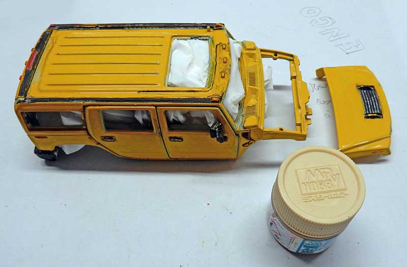 Maquette de Hummer jaune en cours de montage avec capot démonté et pot de peinture