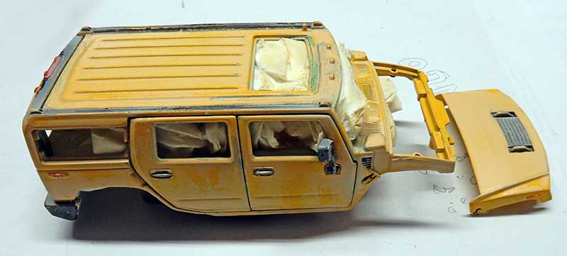 Maquette de Hummer jaune en cours de peinture vieillie, capot démonté posé à côté