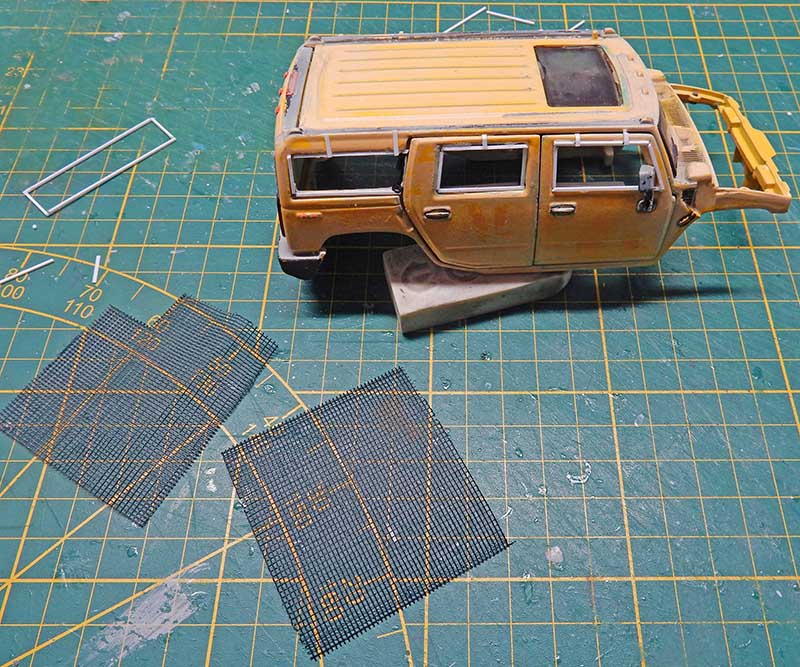Carrosserie de Hummer jaune patinée et grillages de maquette posés sur tapis de découpe