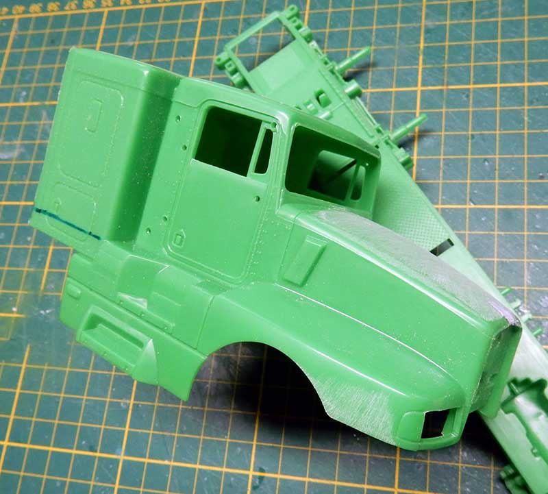 Cabine de camion en maquette plastique vert posée sur tapis de découpe vert quadrillé