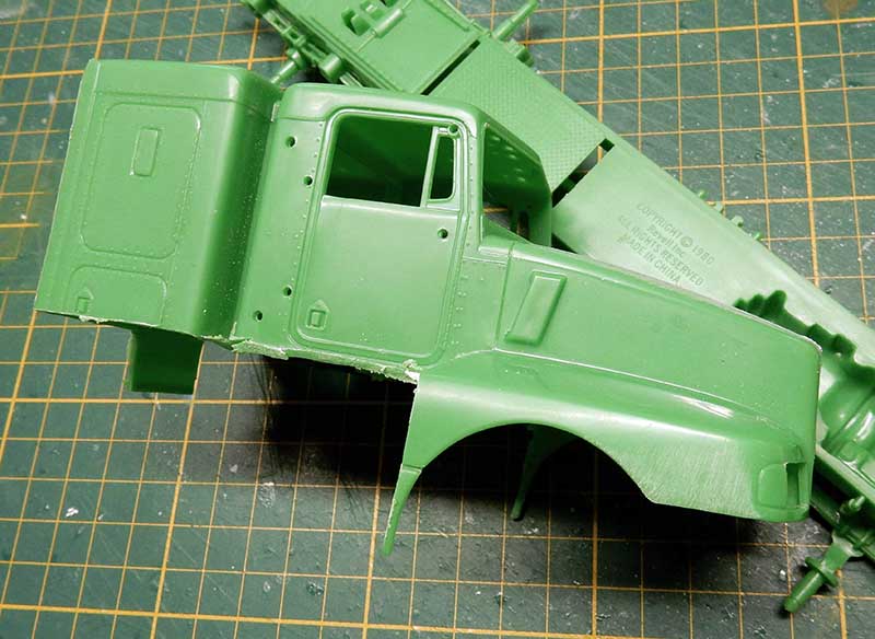 Cabine de camion en plastique vert sur tapis de découpe, pièces de maquette non assemblées