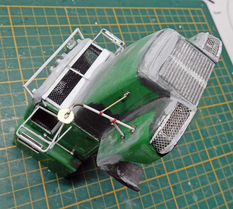 Maquette de véhicule blindé vert avec grilles métalliques et détails peints sur tapis de découpe