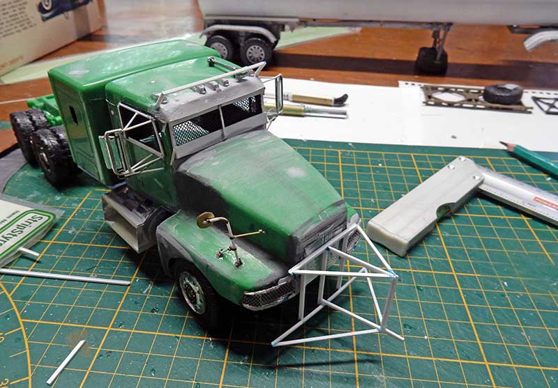 Maquette de camion vert en cours de montage avec arceaux de protection sur tapis de découpe