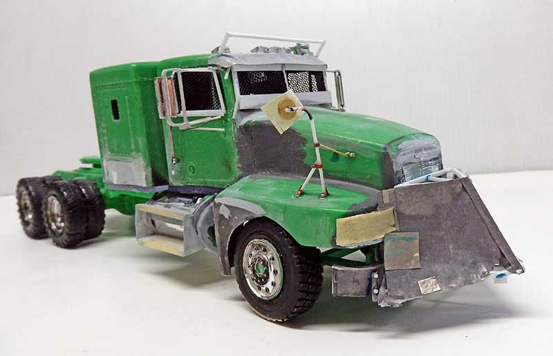 Maquette de camion semi-remorque vert blindé avec lame frontale, grilles aux fenêtres, en cours de fabrication