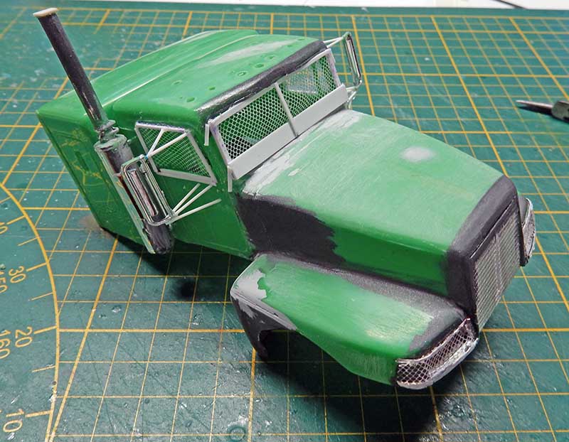 Maquette de cabine de camion vert en cours de peinture sur tapis de découpe