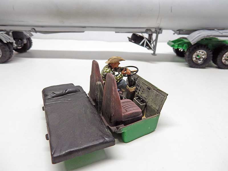 Maquette de buggy vert avec figurine de conducteur au chapeau devant un camion-citerne