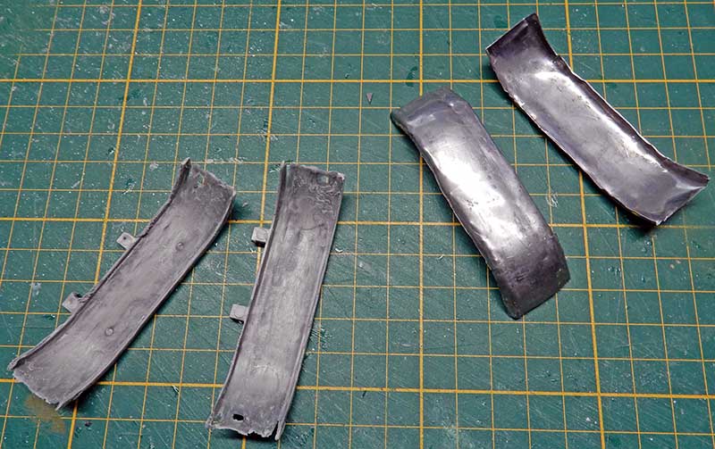Pièces de maquette gris métallisé en cours de montage sur tapis de découpe vert