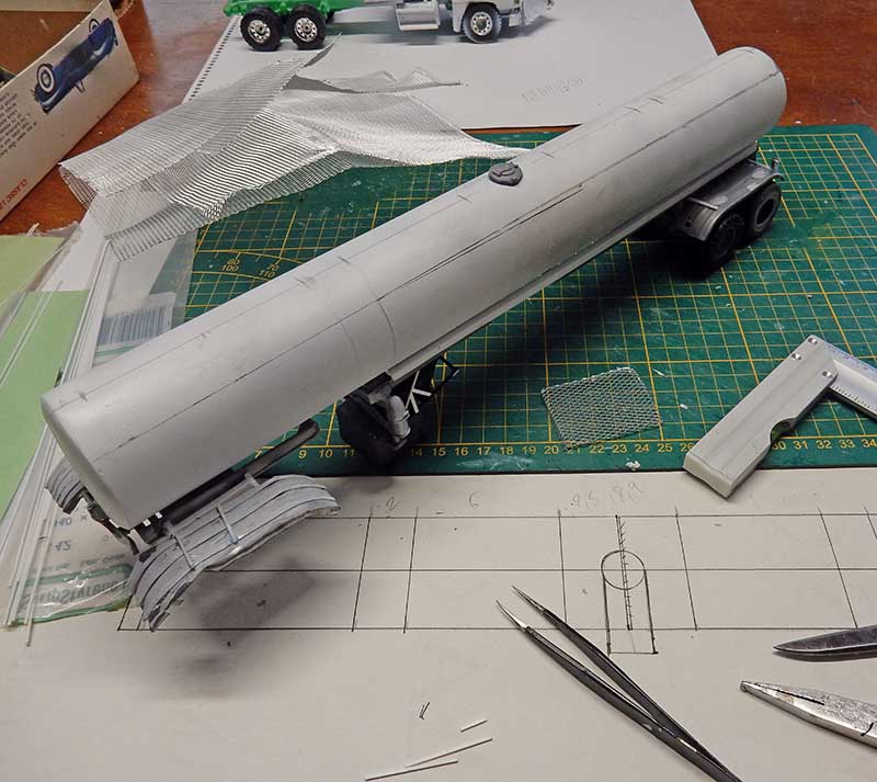Maquette de camion-citerne gris en construction sur tapis de découpe avec outils de modélisme