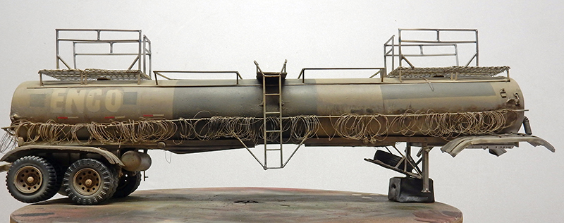 Maquette de citerne-remorque ENCO patinée entourée de barbelés, sur fond clair