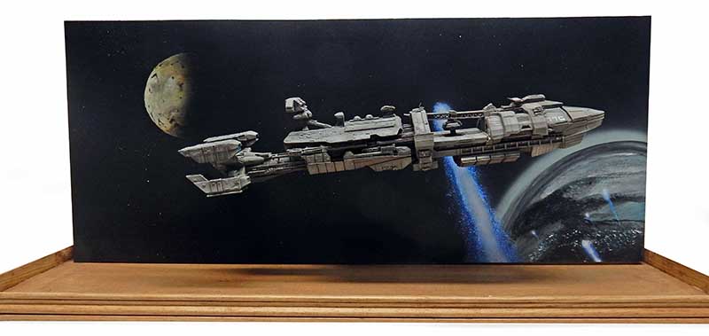 Maquette du vaisseau Rodger Young sur diorama spatial avec planète et fond étoilé