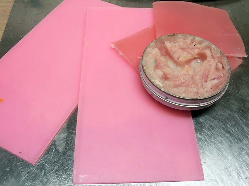 Plaques de cire rose et coupelle de cire à modeler sur plan de travail métallique