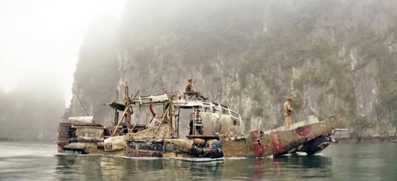 Vieux bateau de pêche avec marins naviguant dans une baie brumeuse près de falaises rocheuses