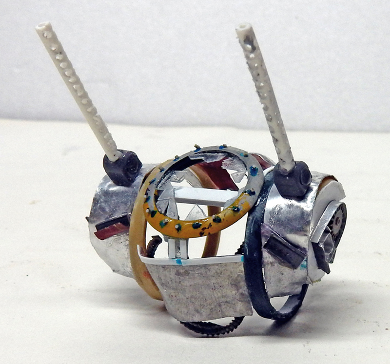 Maquette en construction d'un petit véhicule blindé argenté avec deux antennes et cerclage métallique