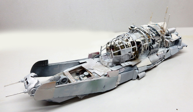 Maquette de bateau de guerre en construction, structure grise détaillée avec passerelle ajourée et armement