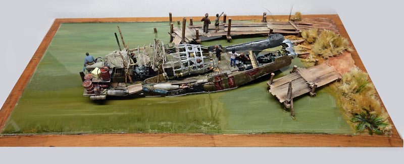 Diorama de maquette représentant un vieux bateau de pêche amarré à un ponton en bois sur une eau verdâtre
