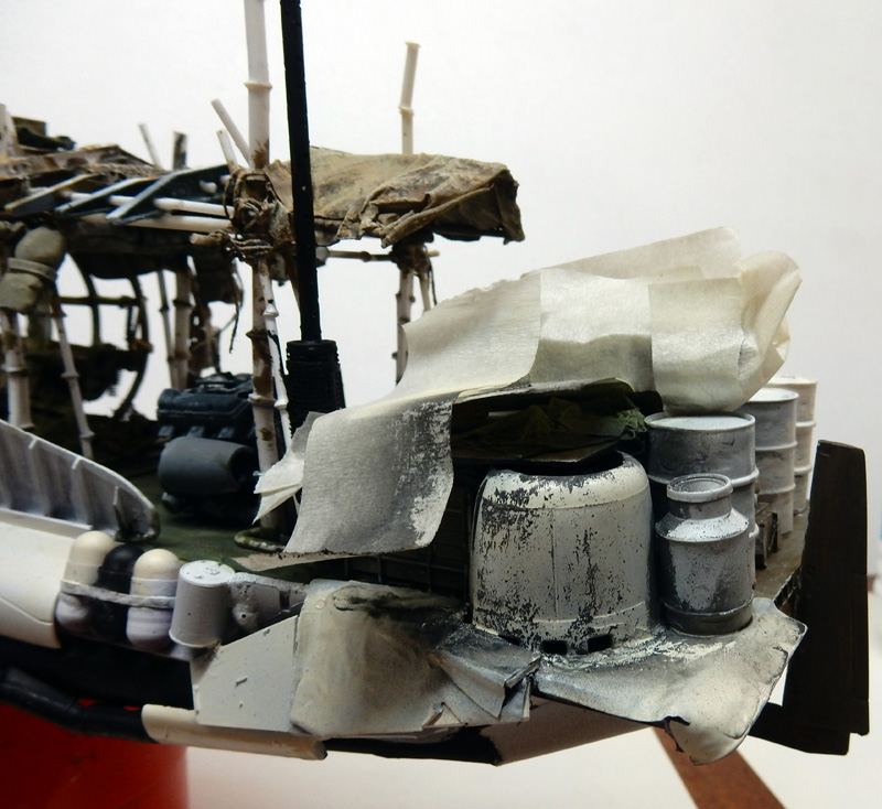 Maquette détaillée de bateau avec bidons métalliques, bâches et structures vieillies sur le pont