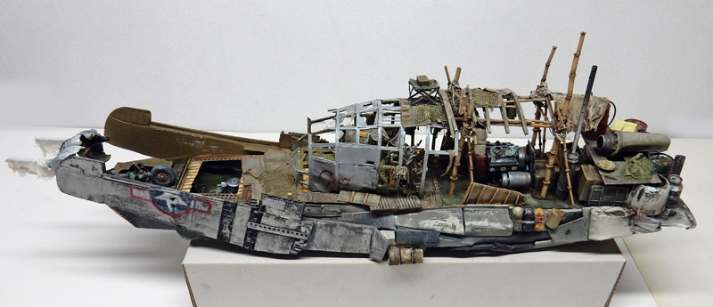 Maquette détaillée de bateau-épave vu de profil, avec structures en bambou et coque vieillie patinée