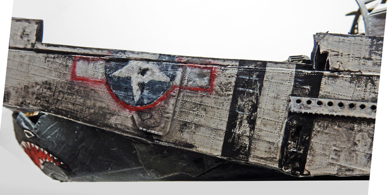 Gros plan sur la coque du bateau faite de fuselage d'avion récupéré, cocarde et gueule de requin