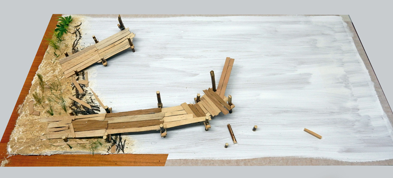 Maquette d'un ponton en bois sur pilotis longeant une plage de sable blanc