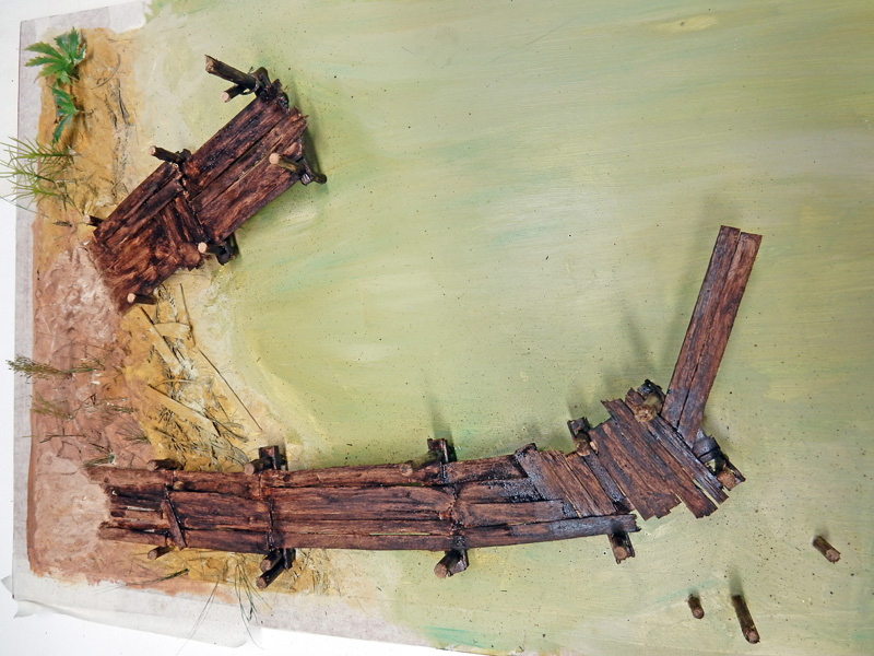 Maquette d'un ponton et d'une épave de bateau en bois sur diorama de plage