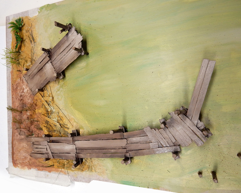 Maquette d'épave de bateau en bois échouée sur une berge sablonneuse végétalisée
