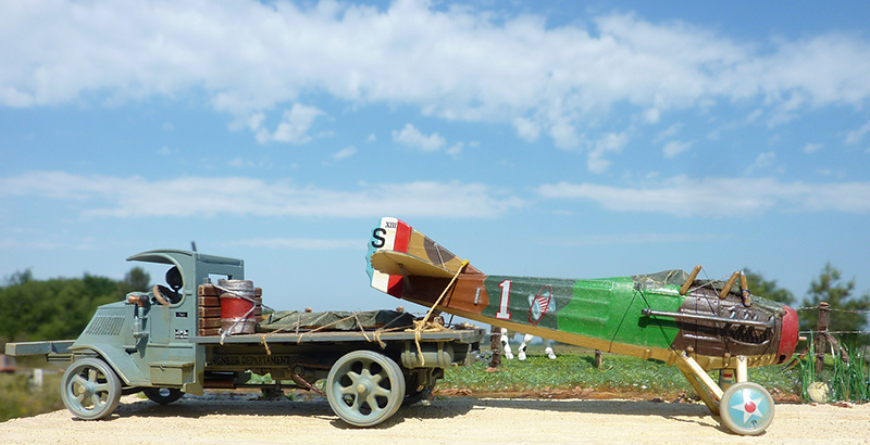Maquette du biplan Spad XIII chargé sur un camion militaire ancien devant un ciel bleu