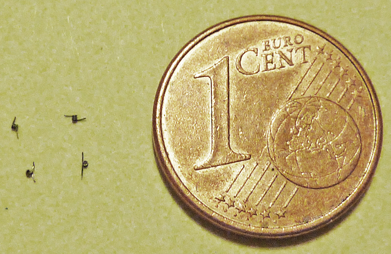 Minuscules pièces de maquette à côté d'une pièce de un centime d'euro pour l'échelle