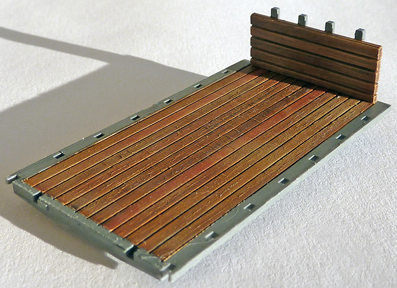Plancher de maquette en lattes de bois imitation, encadré de structures grises avec paroi verticale à l'arrière