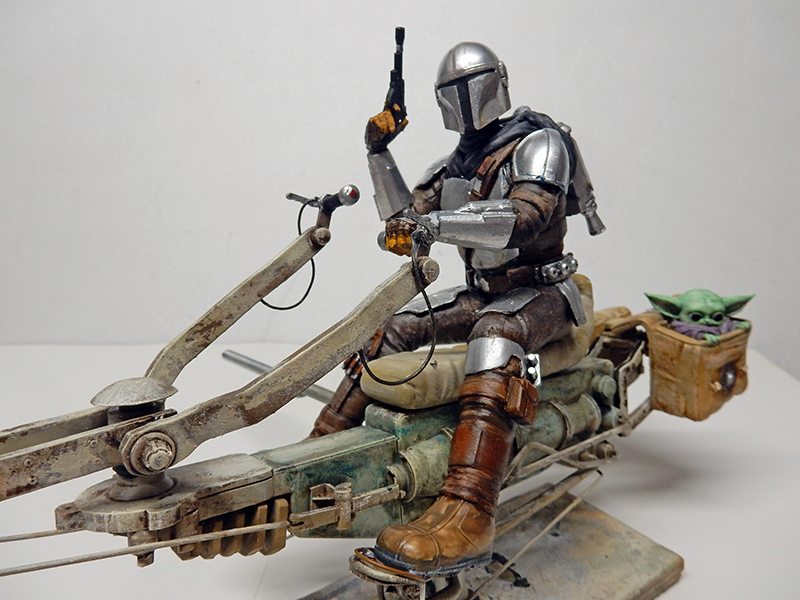 Maquette de speedbike avec chasseur de primes casqué et créature verte, fond neutre