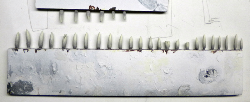 Rangée de dents pointues sculptées et peintes en blanc alignées sur un support