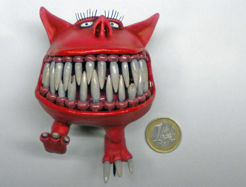 Figurine de Squig rouge aux grandes dents blanches à côté d'une pièce d'un euro