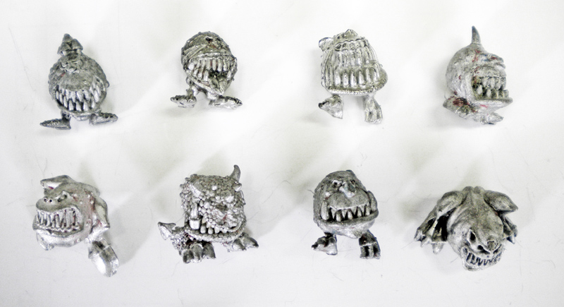 Huit figurines de Squigs en métal nu non peintes alignées sur fond blanc