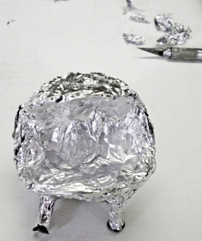 Structure de Squig en papier aluminium façonné avec scalpel et chutes posées à côté