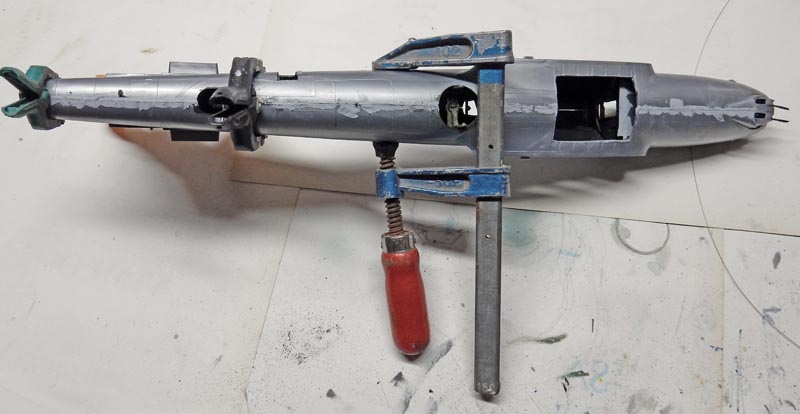 Fuselage gris du Streamliner maintenu par un serre-joint pendant le collage des demi-coques