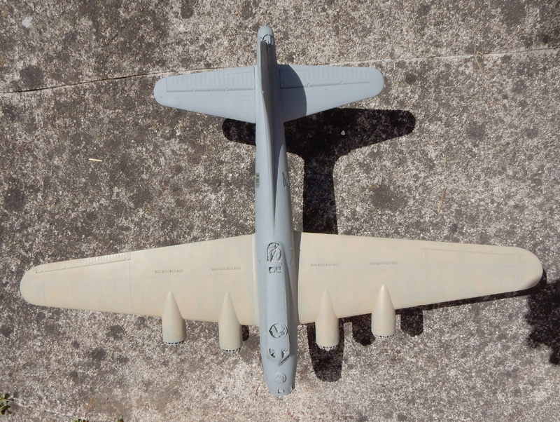 Maquette d'avion quadrimoteur vue de dessus posée sur béton, fuselage gris et beige