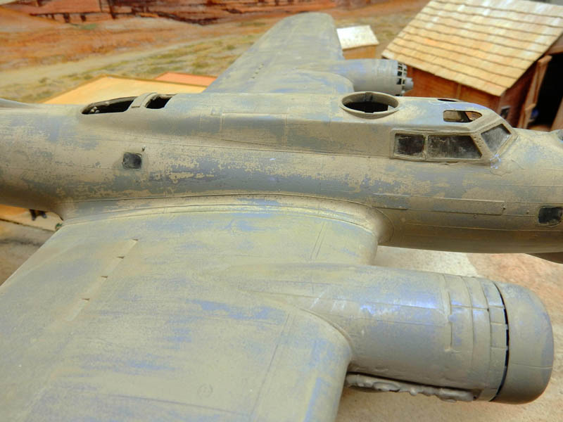 Maquette d'avion bombardier gris vieilli en cours de patine, vue rapprochée du fuselage et de l'aile
