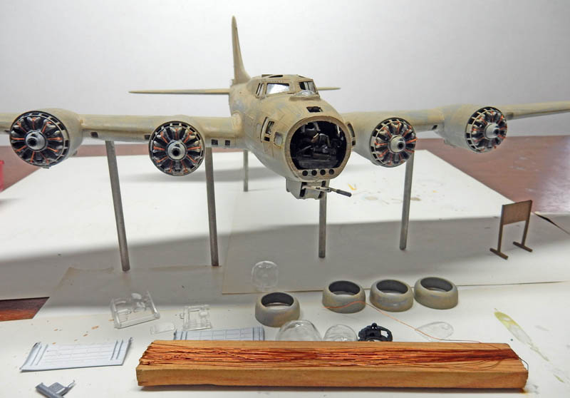 Maquette de bombardier quadrimoteur en construction avec moteurs en étoile et pièces détachées sur l'établi