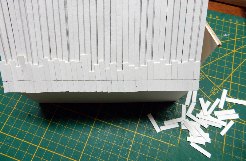 Maquette en carton à lamelles découpées sur tapis de coupe vert avec chutes