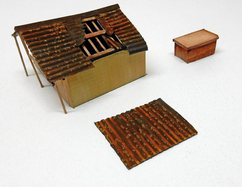 Maquette de cabane au toit de tôle ondulée rouillée avec plaque et caisse en bois