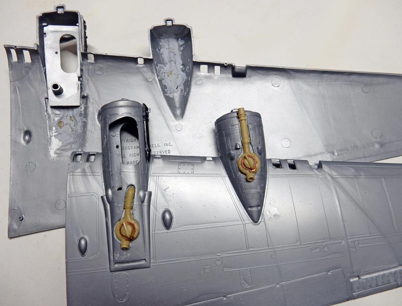 Pièces de maquette grises d'ailes d'avion avec logements de train d'atterrissage et détails résine