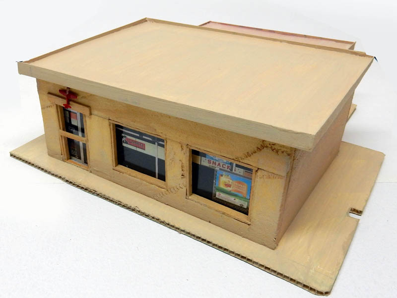 Maquette en carton d'un snack-bar au toit plat avec vitrines, en cours de construction
