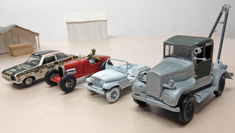 Maquettes de véhicules dont un camion dépanneuse gris, une jeep, un roadster rouge et une voiture de rallye