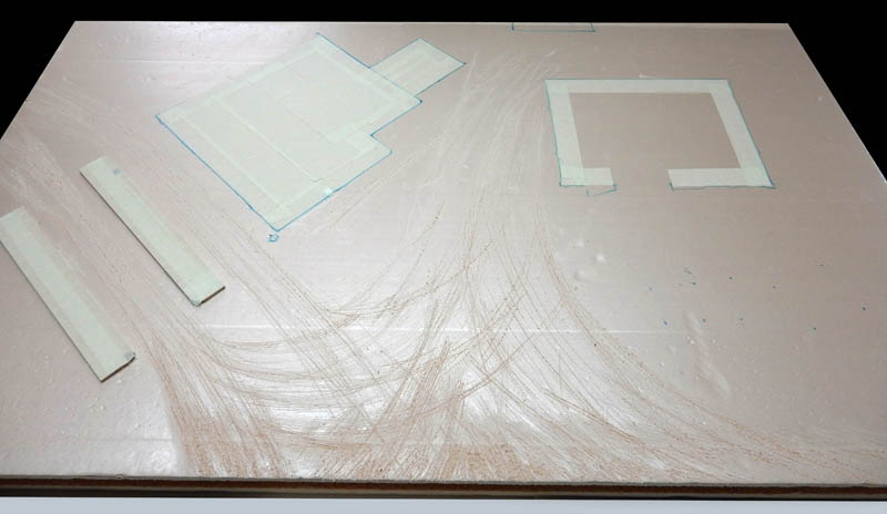 Pièces de carte plume découpées posées sur une planche avec tracés au crayon
