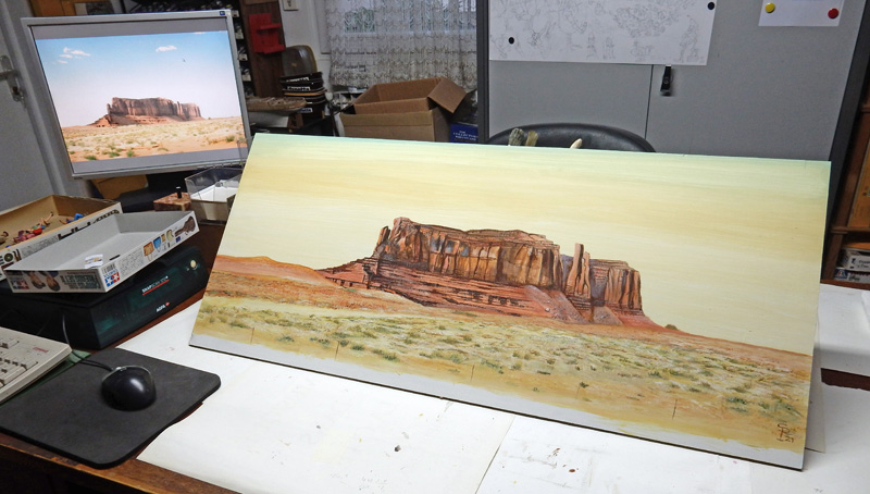 Décor de fond peint représentant Monument Valley avec photo de référence sur l'écran d'atelier