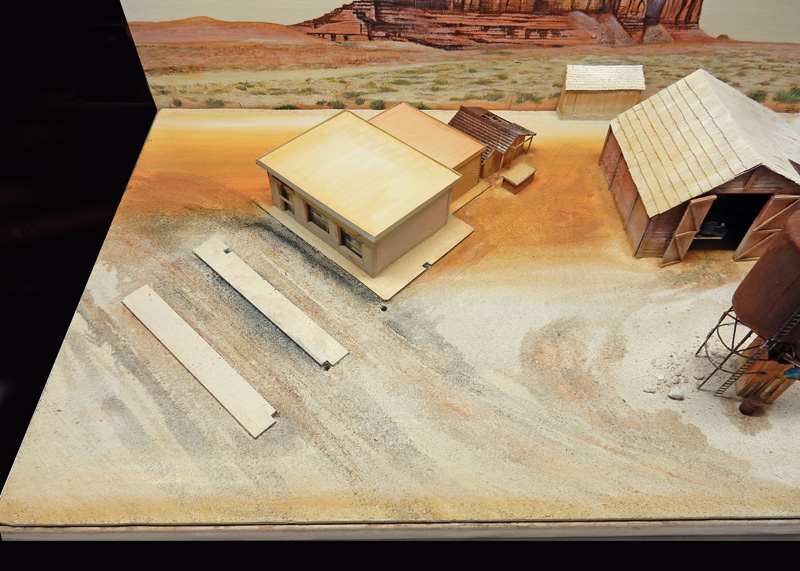 Maquette de diorama désertique avec bâtiments en bois et décor de plateau rocheux en arrière-plan