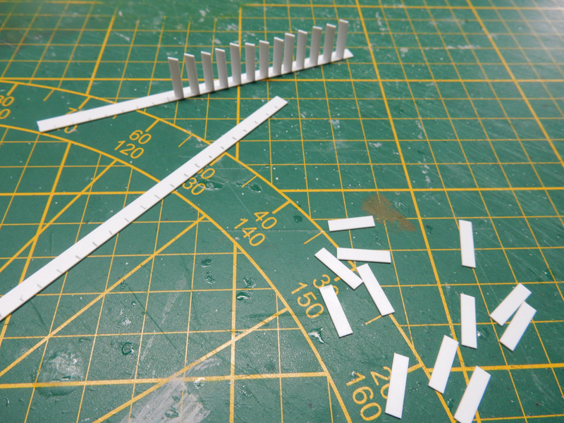 Bandes et petits éléments de plasticard découpés sur un tapis de coupe vert
