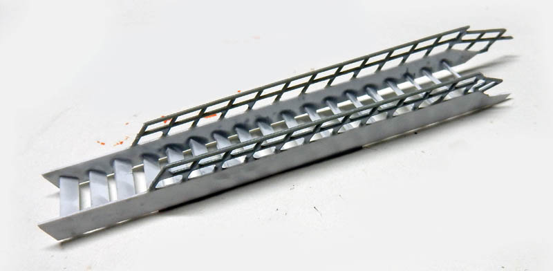 Pièces de grille photodécoupées grises pour maquette Streamliner posées sur fond blanc