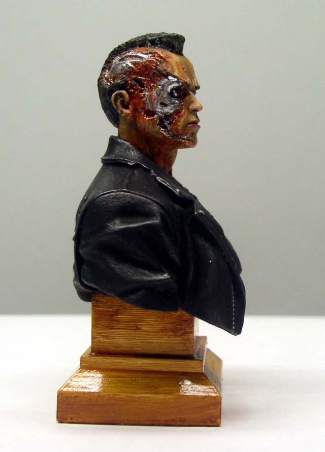 Buste peint du T800 de profil, visage écorché révélant le crâne métallique, sur socle bois